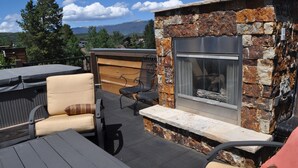 An outdoor patio with stone walls, a built-in fireplace, and seating areas. - Gorgeous Mountain Modern Home~ Private Rooftop Hot Tub, Fireplace & 360 Views!!! (Frisco)