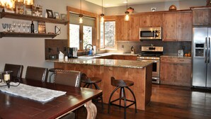 A modern kitchen with wooden cabinets, stainless steel appliances, and a central island with bar stools. - Gorgeous Mountain Modern Home~ Private Rooftop Hot Tub, Fireplace & 360 Views!!! (Frisco)