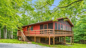 A cabin with a wooden deck, a staircase, and a large window. - River Cabin w/hot tub, fire pit, deck, games, wifi (Great Cacapon)