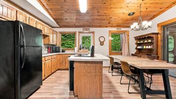 Eine Küche mit Holzausstattung, einem schwarzen Kühlschrank, einer Mikrowelle und einem Essbereich mit Holztisch und Stühlen.