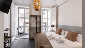 Ein Hotelzimmer mit Bett, Schreibtisch, Stuhl, Kleiderschrank und einer Pendelleuchte.