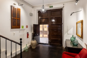 Um corredor com uma porta de madeira, um extintor de incêndio e uma cadeira vermelha.