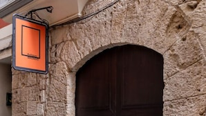 Ein Steingebäude mit dunklem, rundbogigen Eingang und einem Schild, das auf ein historisches Gebäude hinweist.