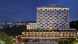 A high-rise hotel with multiple floors, a prominent "MONDRIAN" sign, and a well-lit entrance area. - Mondrian Seoul Itaewon (Seoul)