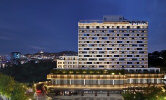 A high-rise hotel with multiple floors, a prominent "MONDRIAN" sign, and a well-lit entrance area.
