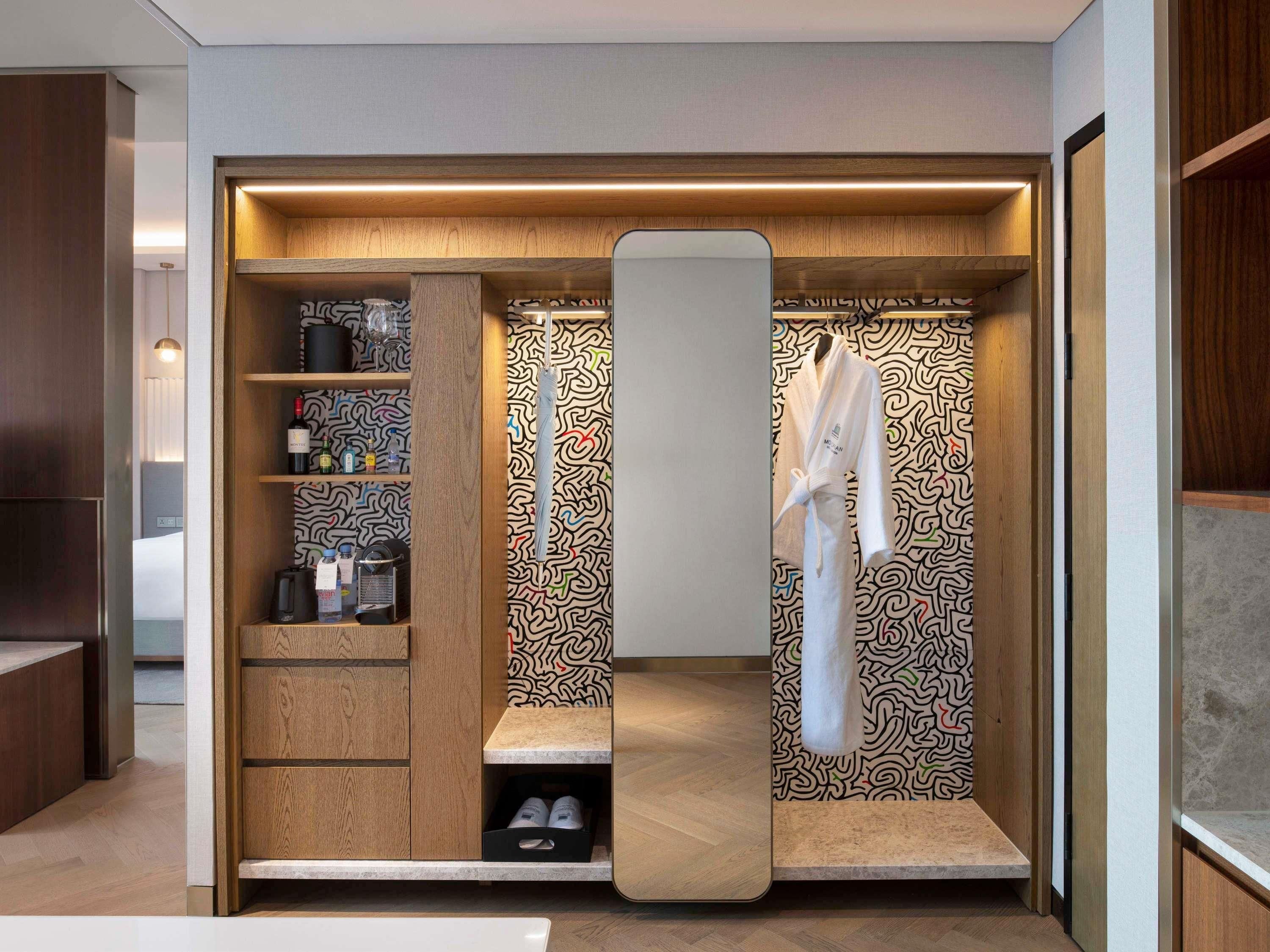 Ein begehbarer Kleiderschrank mit Holzböden, einem Spiegel und einem aufgehängten Bademantel.