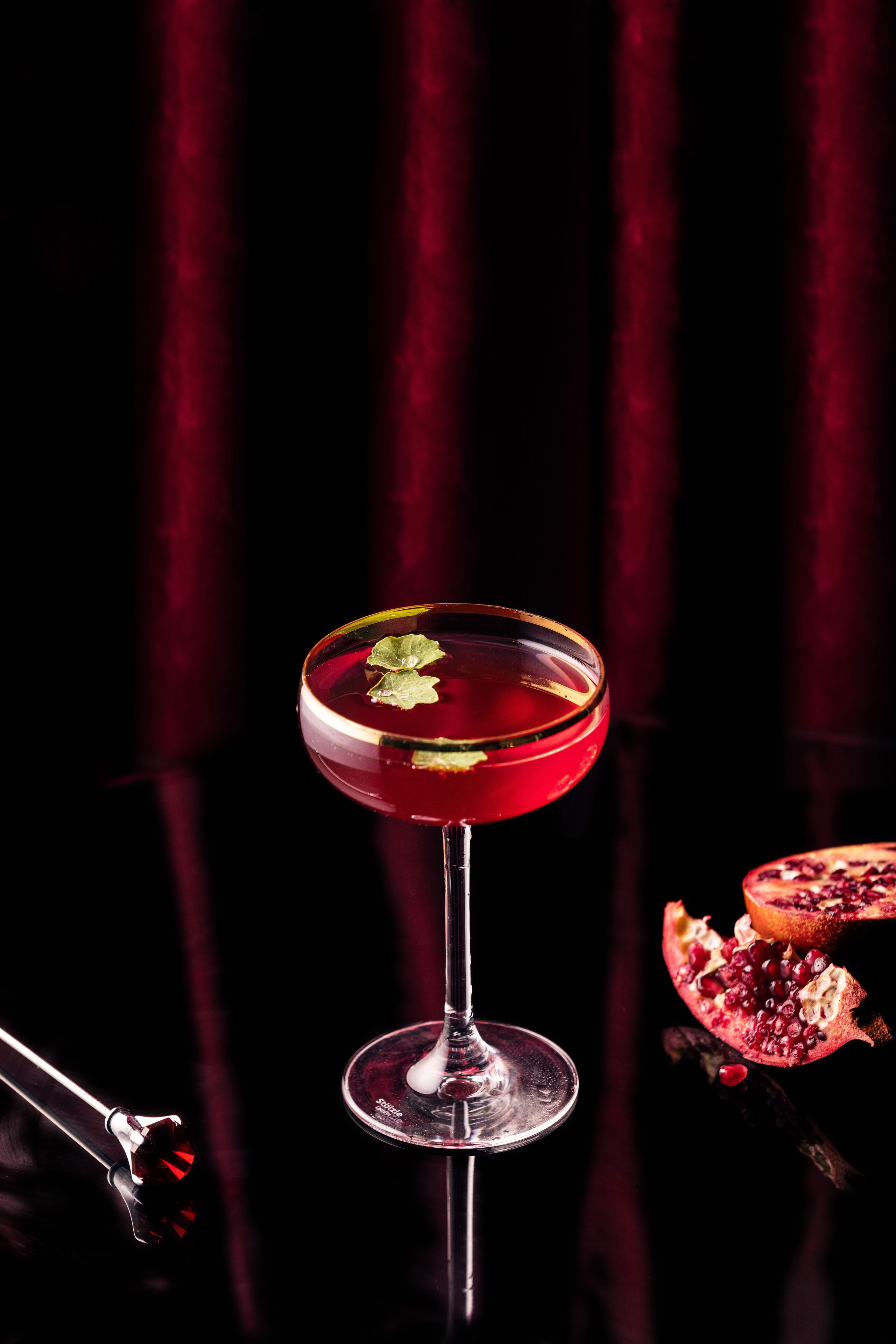 Een cocktailglas met garnering op een reflecterend oppervlak.