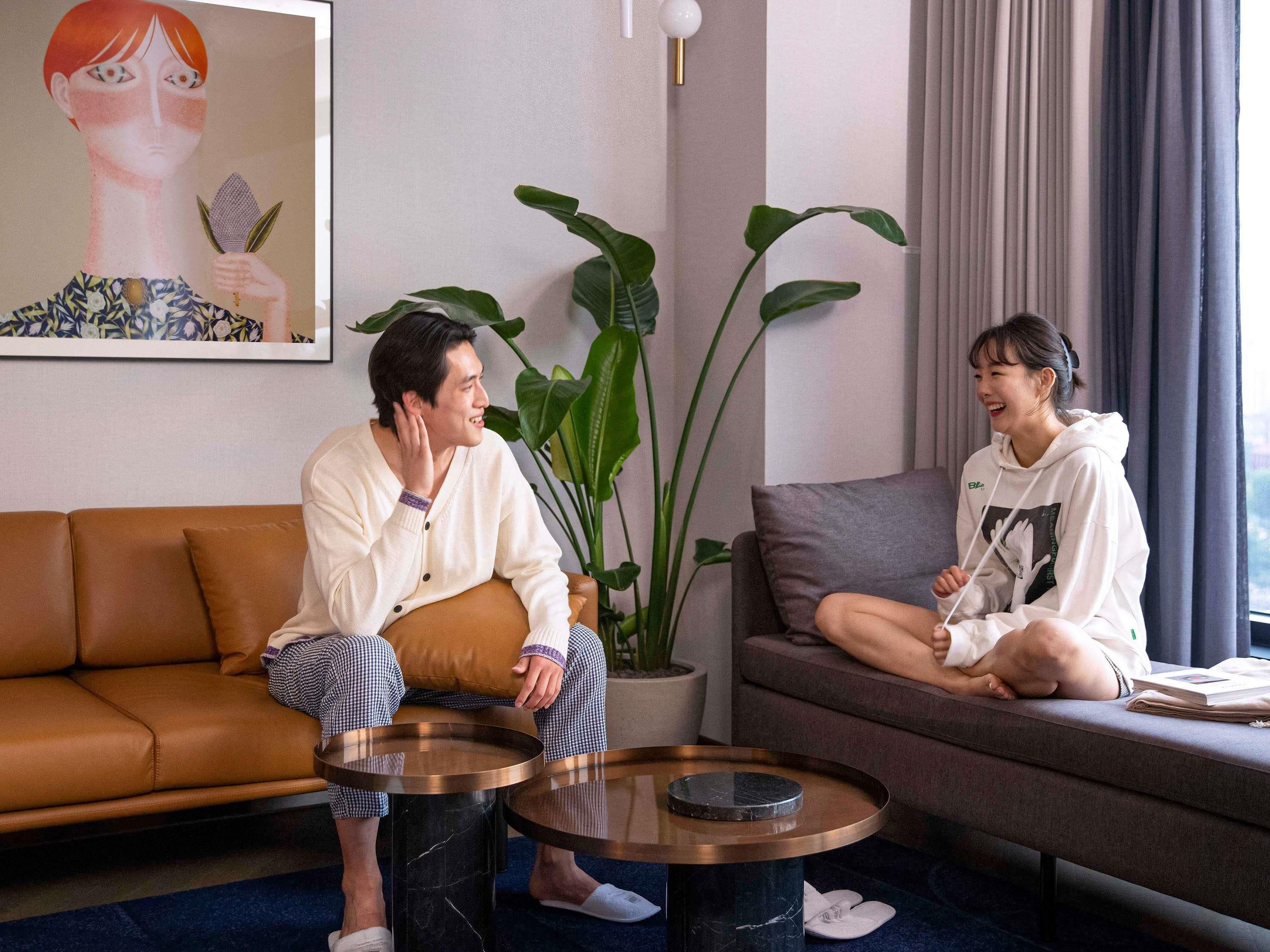 A living room with a brown sofa, a grey couch, a round coffee table, and a potted plant.