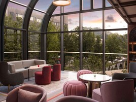 A modern lounge with a curved glass ceiling, offering expansive views of the surrounding greenery and cityscape.