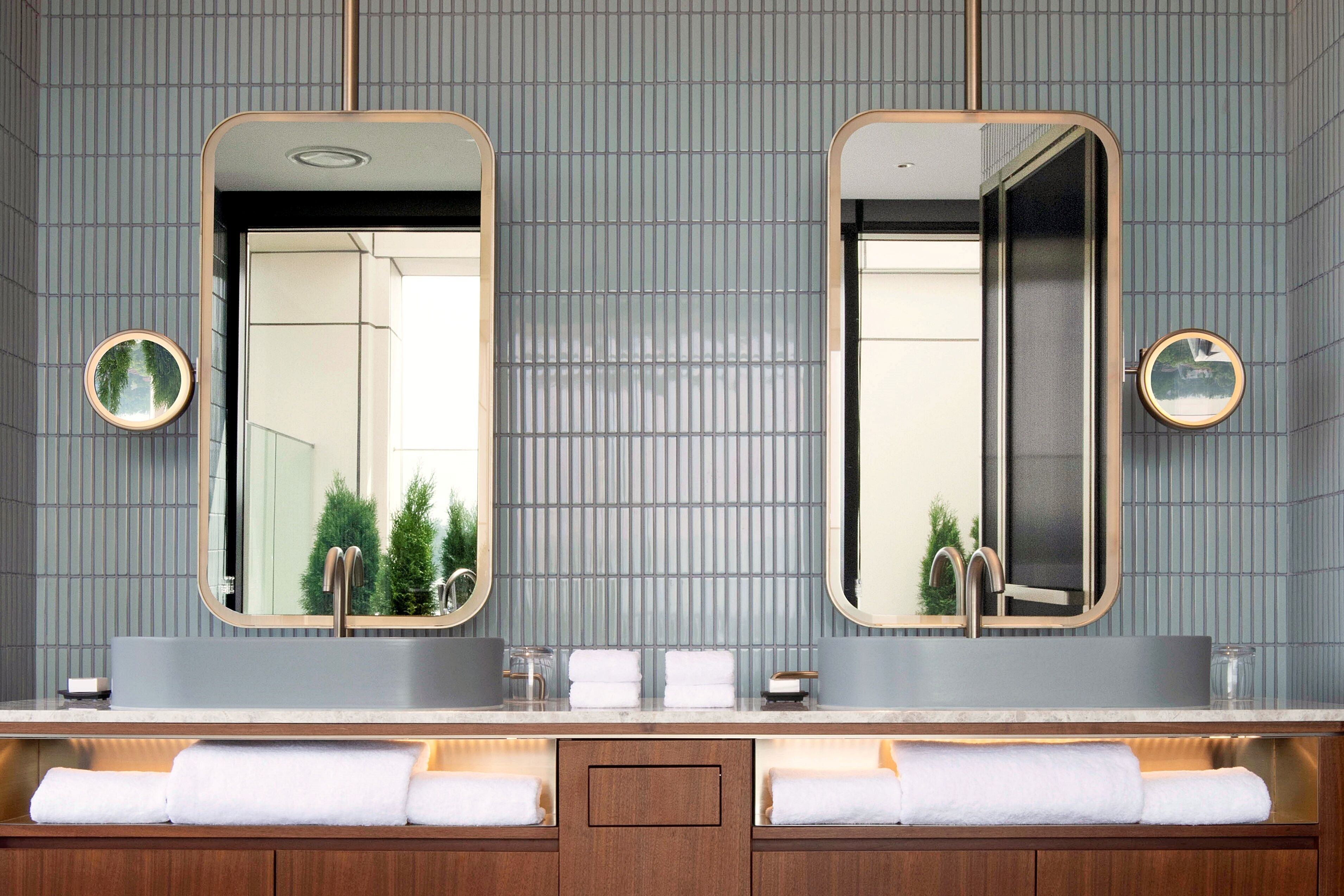 A bathroom with two mirrors, a sink, and a vanity with towels.