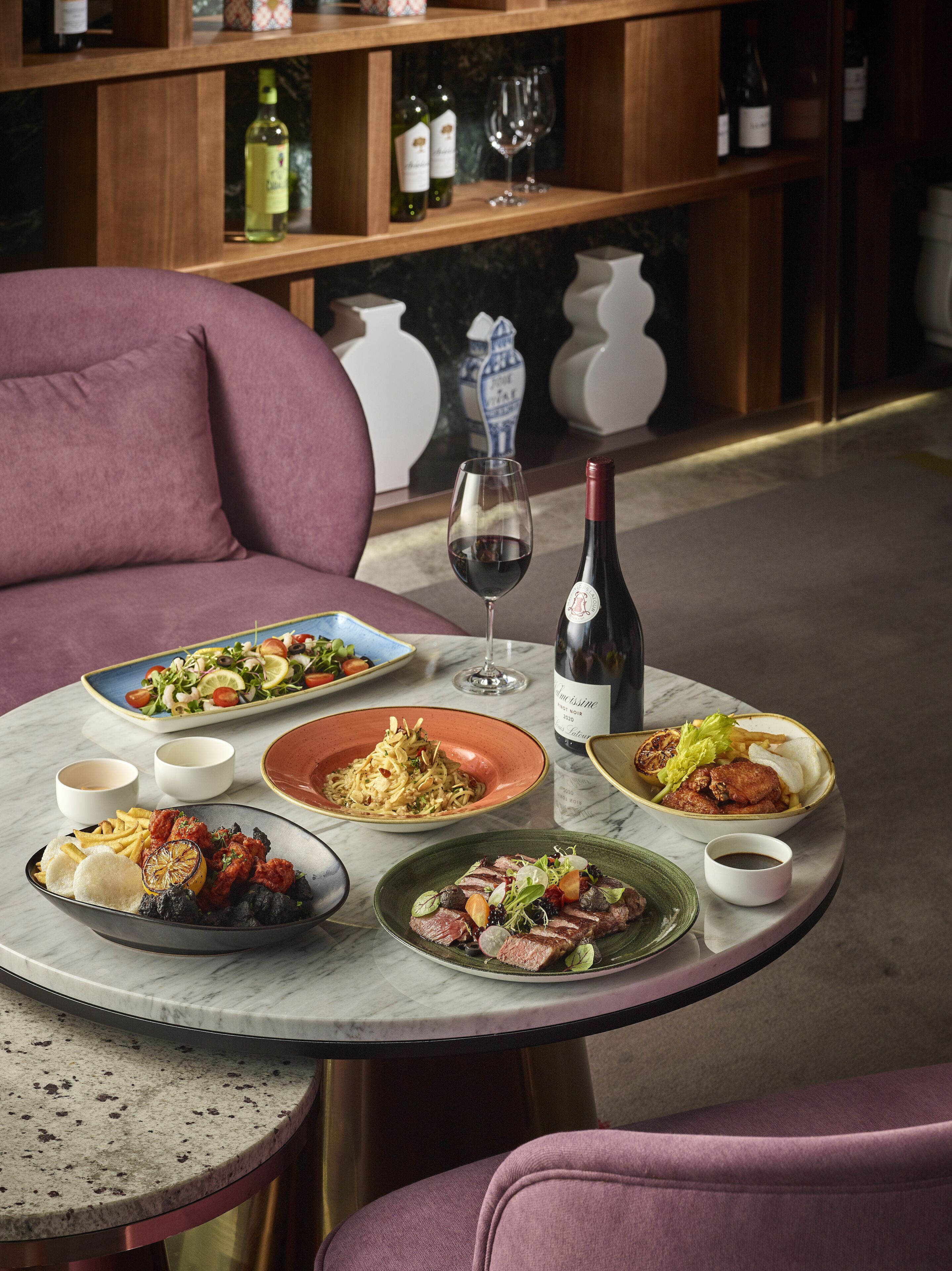 Une table à manger avec différents plats, une bouteille de vin et un verre à vin.