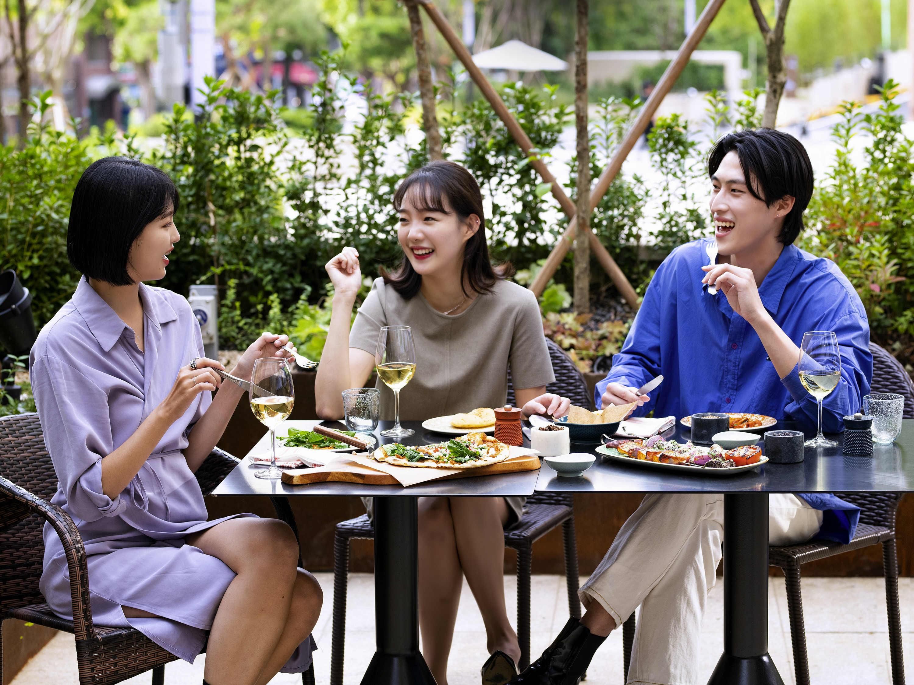 Un grupo de personas cenando al aire libre en una mesa con diversos platos y bebidas.