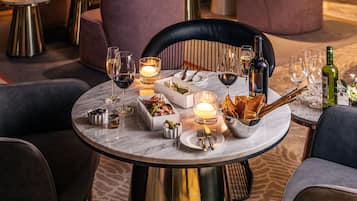 A restaurant with round tables, plush seating, and a wine and cheese board.