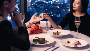 A couple dining at a table with a city view at night.