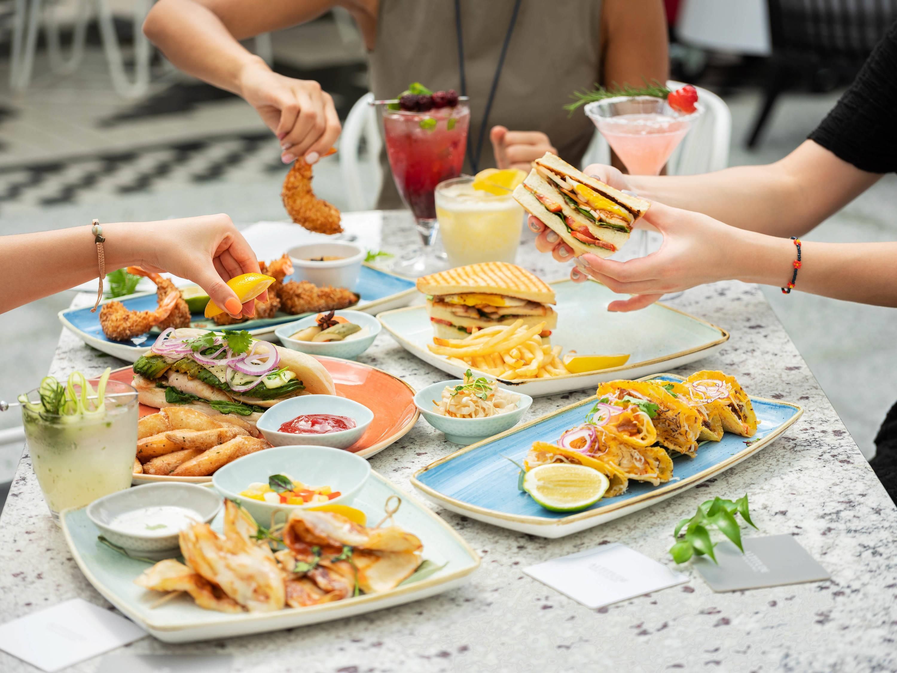 A table with various dishes including sandwiches, fries, and a drink.