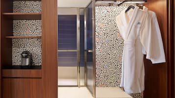 A walk-in closet with patterned wallpaper, a robe hanging on a rack, and a mirror.