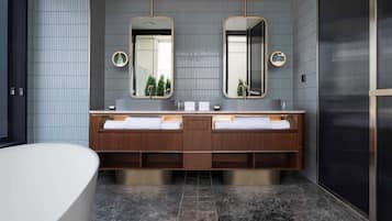 A modern bathroom with a double vanity, two mirrors, and a freestanding bathtub.