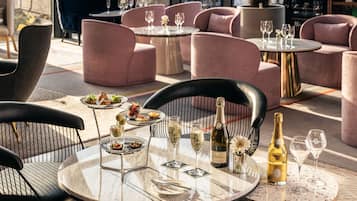 A dining area with round tables, chairs, and a bottle of champagne.