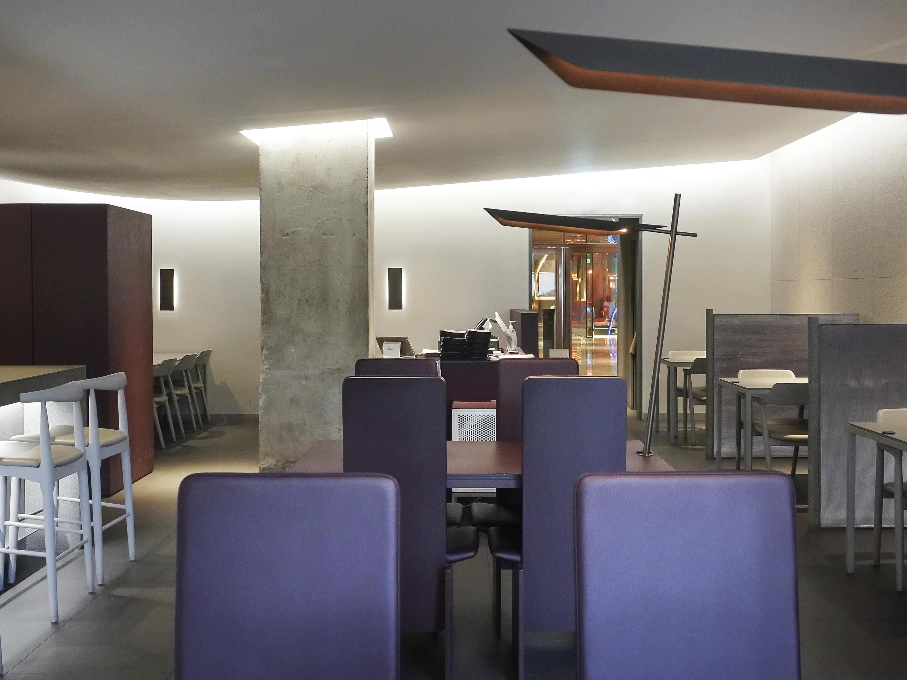 A modern interior with a central pillar, seating arrangements, and a visible entrance.