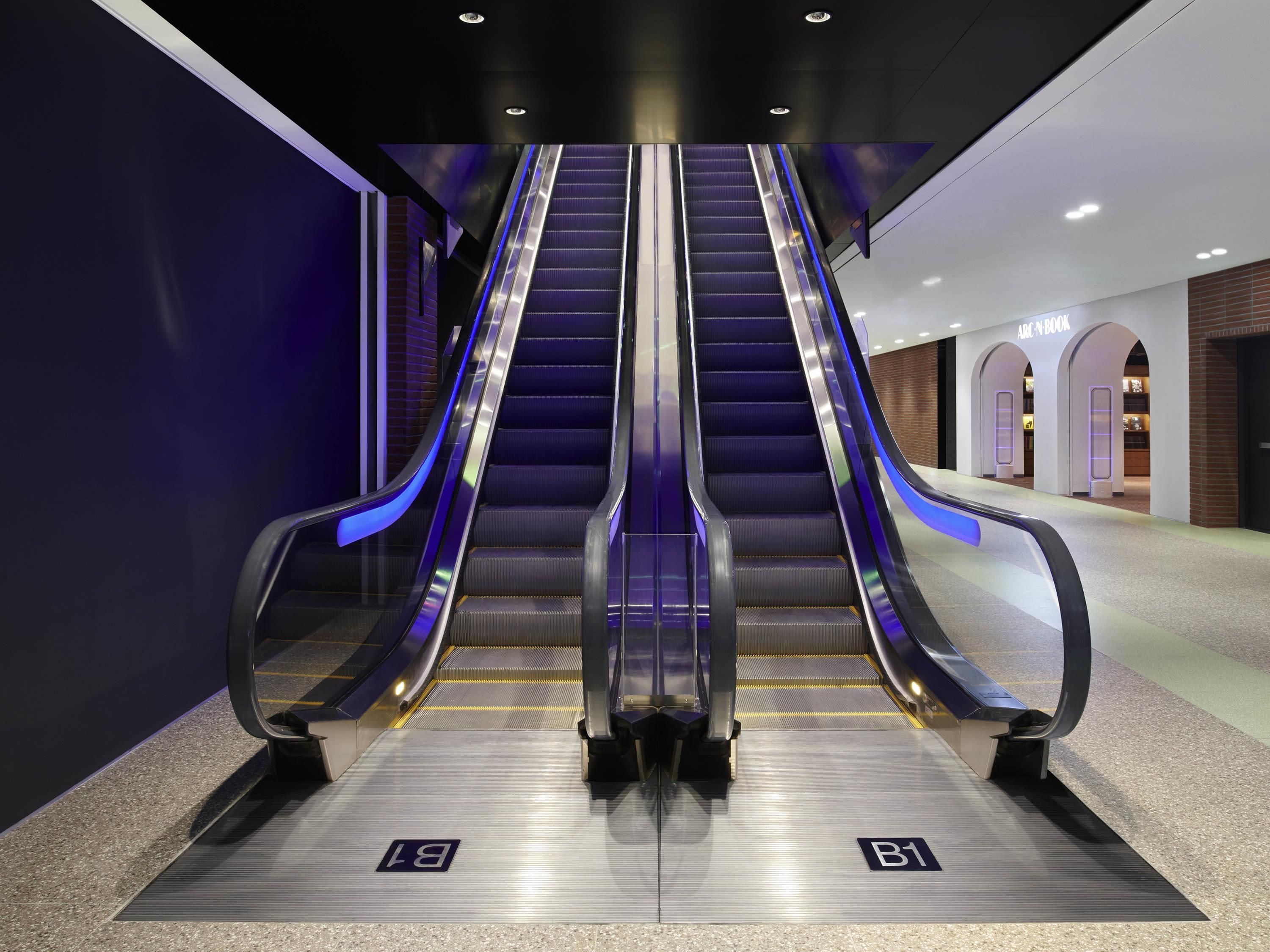 Eine Rolltreppe in einem modernen Gebäude, wobei der Weg mit B1 und B2 gekennzeichnet ist.