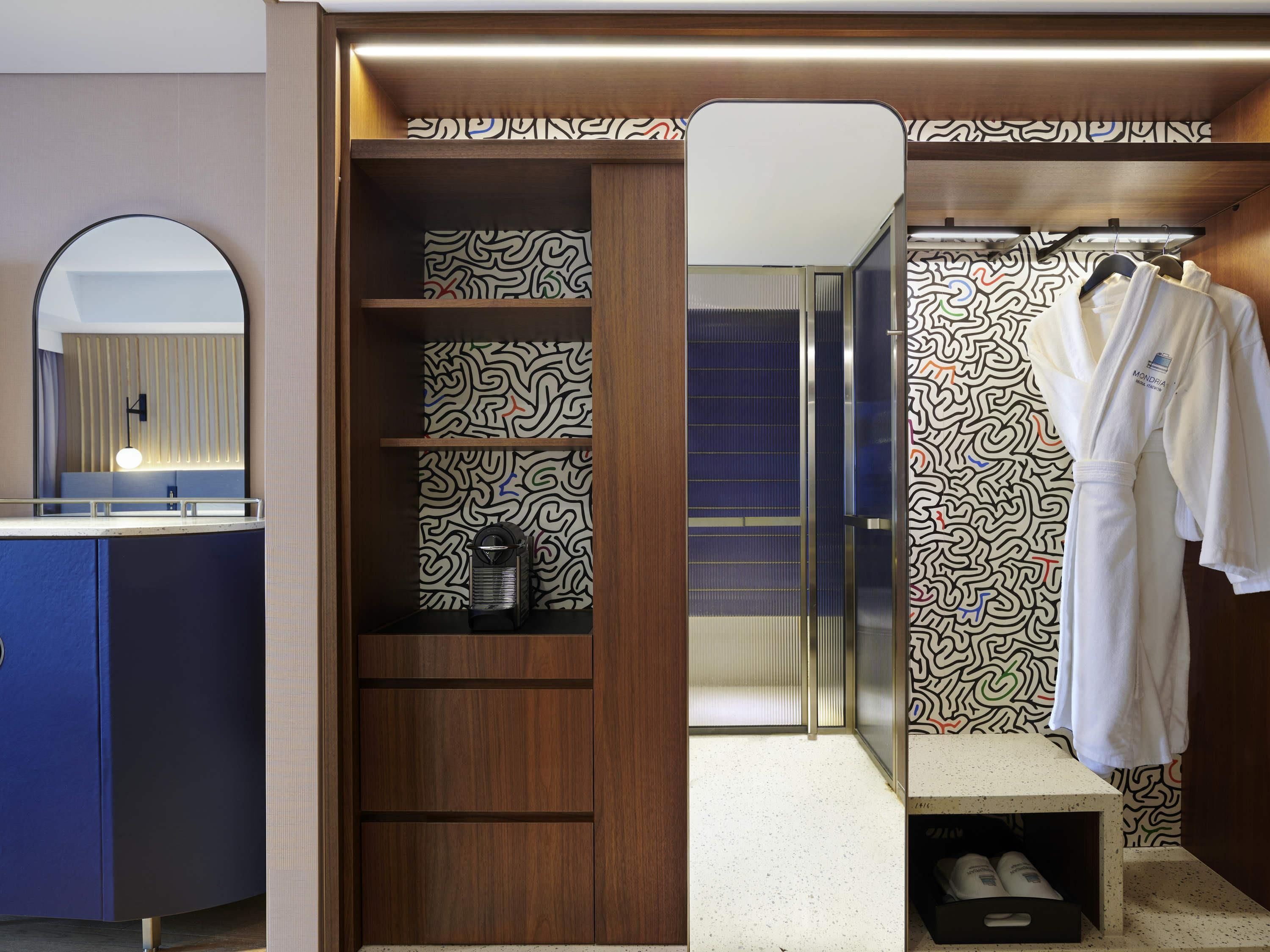 A modern bathroom with a vanity, a mirror, a shower area, and a robe hanging on a rack.