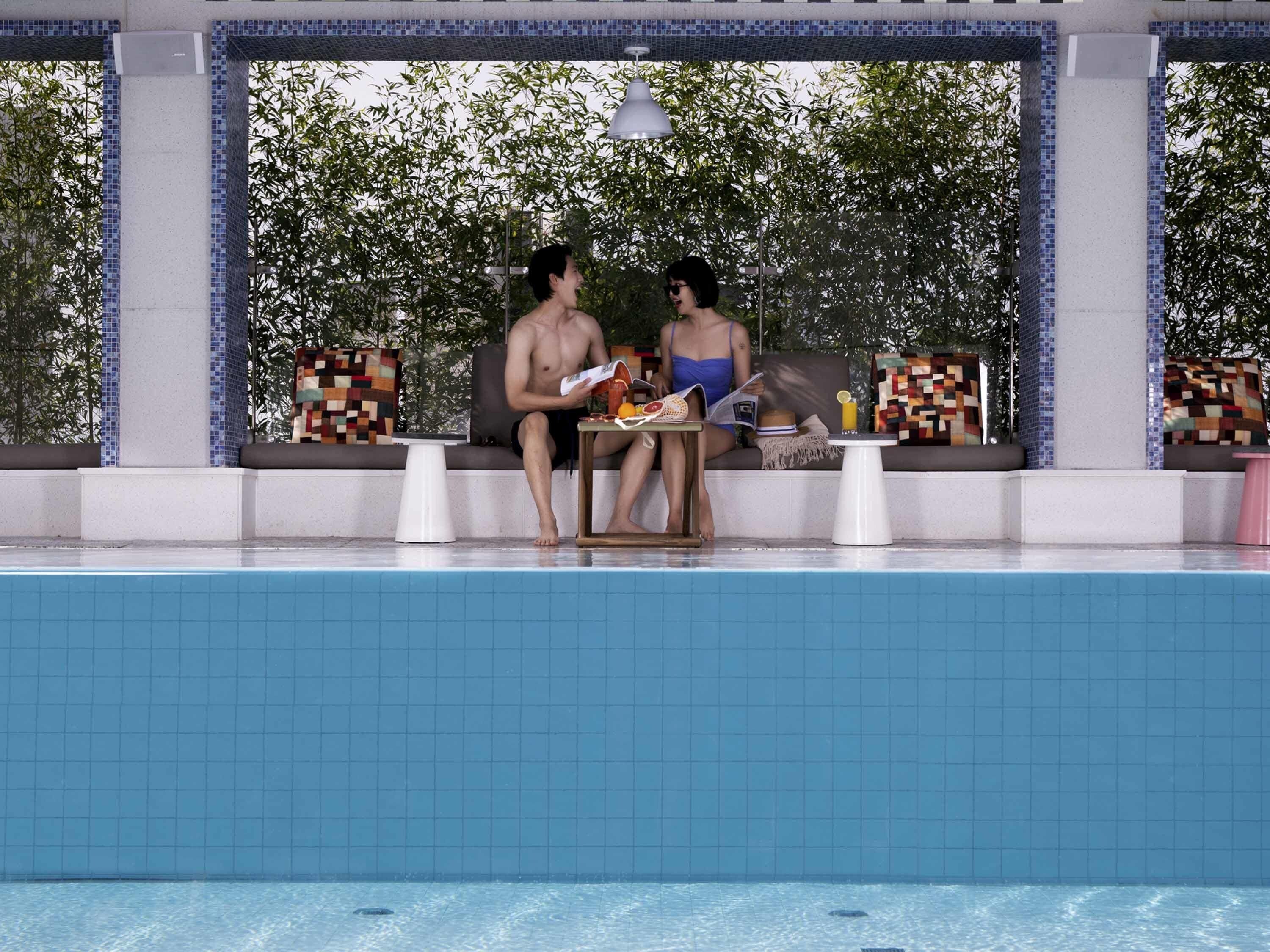 A poolside area with seating and a tiled wall.