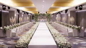 A long banquet hall with a central aisle, rows of tables on either side, and floral arrangements. - Mondrian Seoul Itaewon (Seoul)