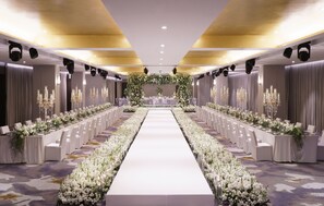 A long banquet hall with a central aisle, rows of tables on either side, and floral arrangements. - Mondrian Seoul Itaewon (Seoul)