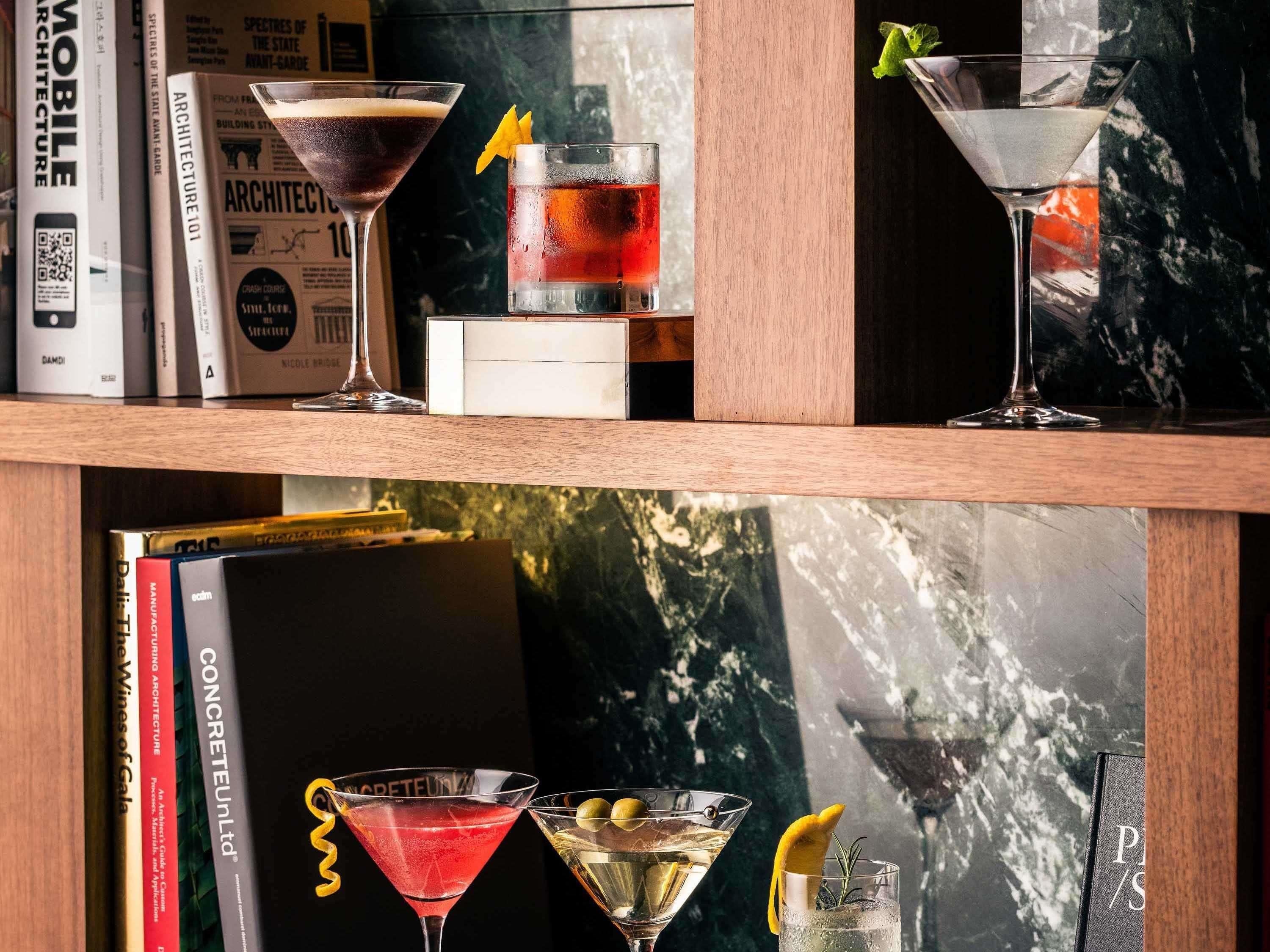 A bookshelf with books and three martini glasses with garnishes.