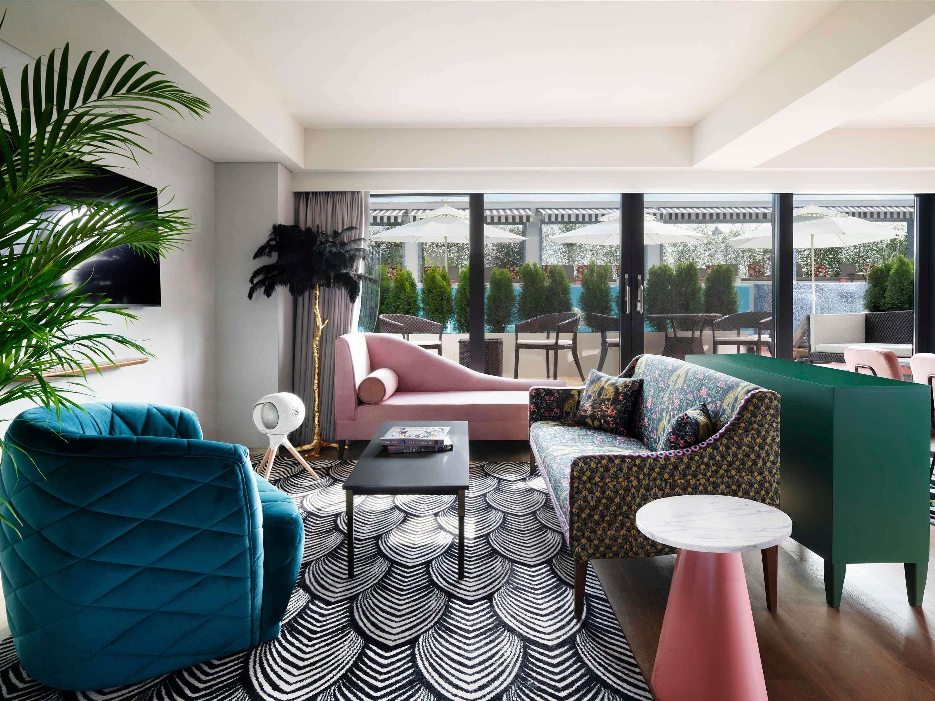 A modern lounge area with a sofa, armchair, and a patterned rug.