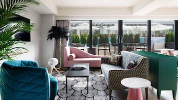 A modern lounge area with a sofa, armchair, and a patterned rug.