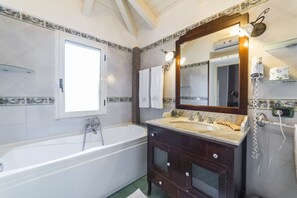 A bathroom with a bathtub, a vanity with a mirror, and a towel rack. - B&B La Magnolia (Castellabate)