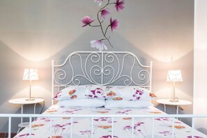 A bed with a floral bedspread, two bedside lamps, and a decorative branch on the wall.