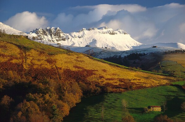 A mountainous landscape with snow-capped peaks, a green valley, and a small building in the foreground. - La Casa de Bustantegua (Selaya)