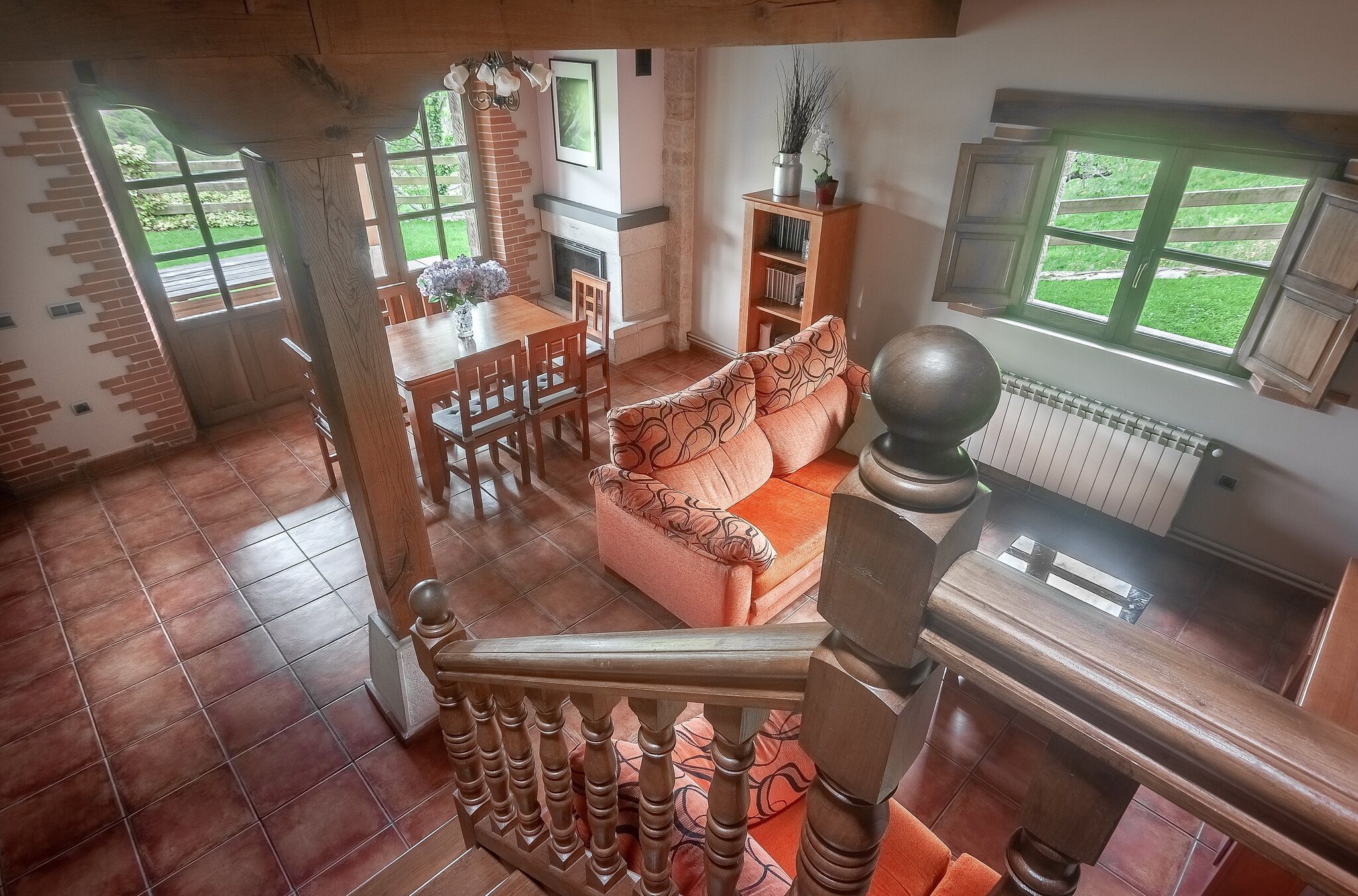 Ein großzügiger Wohnbereich mit Kamin, einer Couch, einem Esstisch mit Stühlen und einer Treppe.