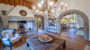 A cozy living room with a fireplace, wooden furniture, and a chandelier.