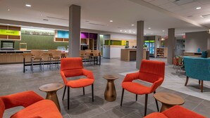 A spacious lobby with modern orange chairs, a reception desk, and a variety of seating options. - Home2 Suites by Hilton Wayne, NJ (Wayne)