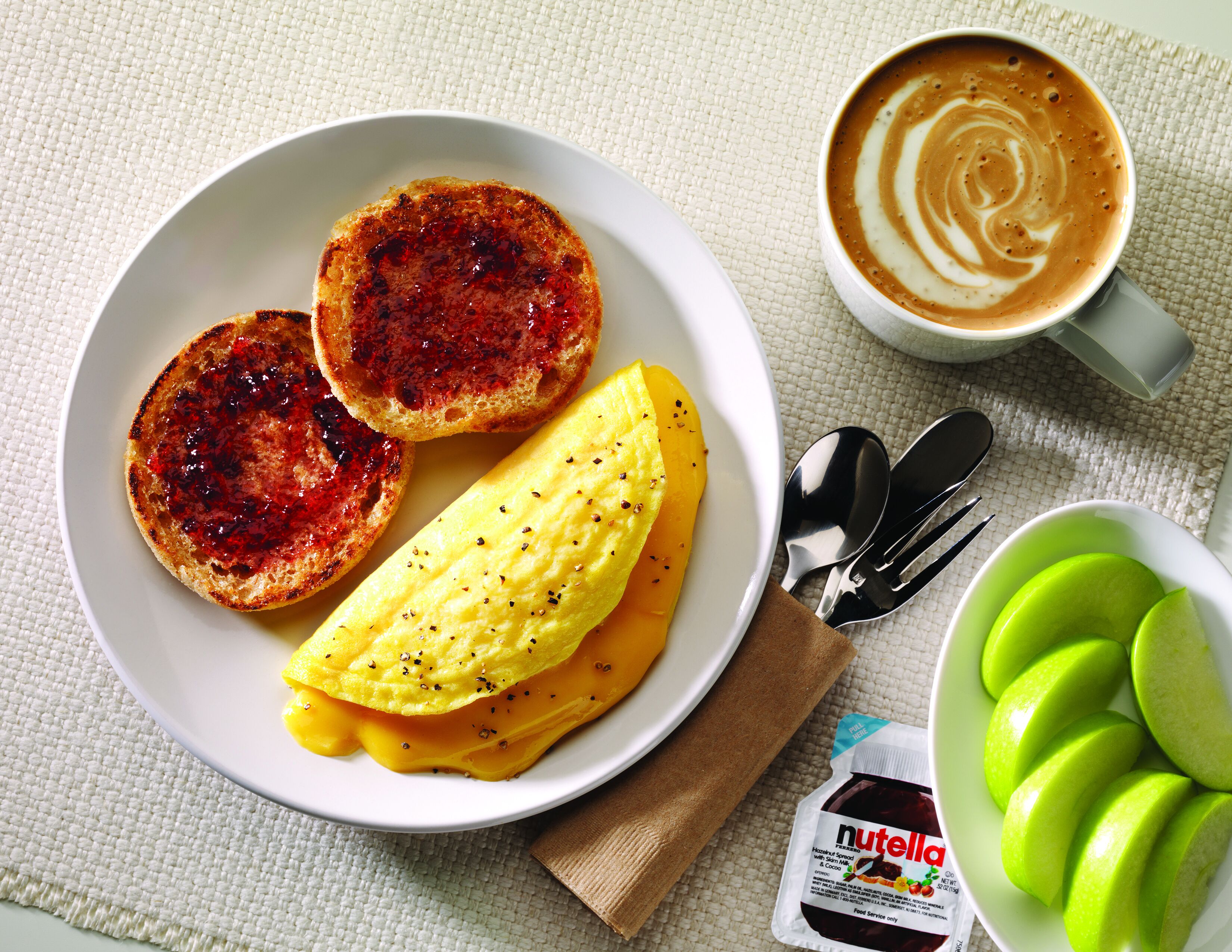 A breakfast plate with toast, scrambled eggs, and a bowl of sliced apples.