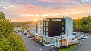 A modern hotel building with a sign reading "HOME 2 SUITES BY HILTON" and a parking lot with cars. - Home2 Suites by Hilton Wayne, NJ (Wayne)