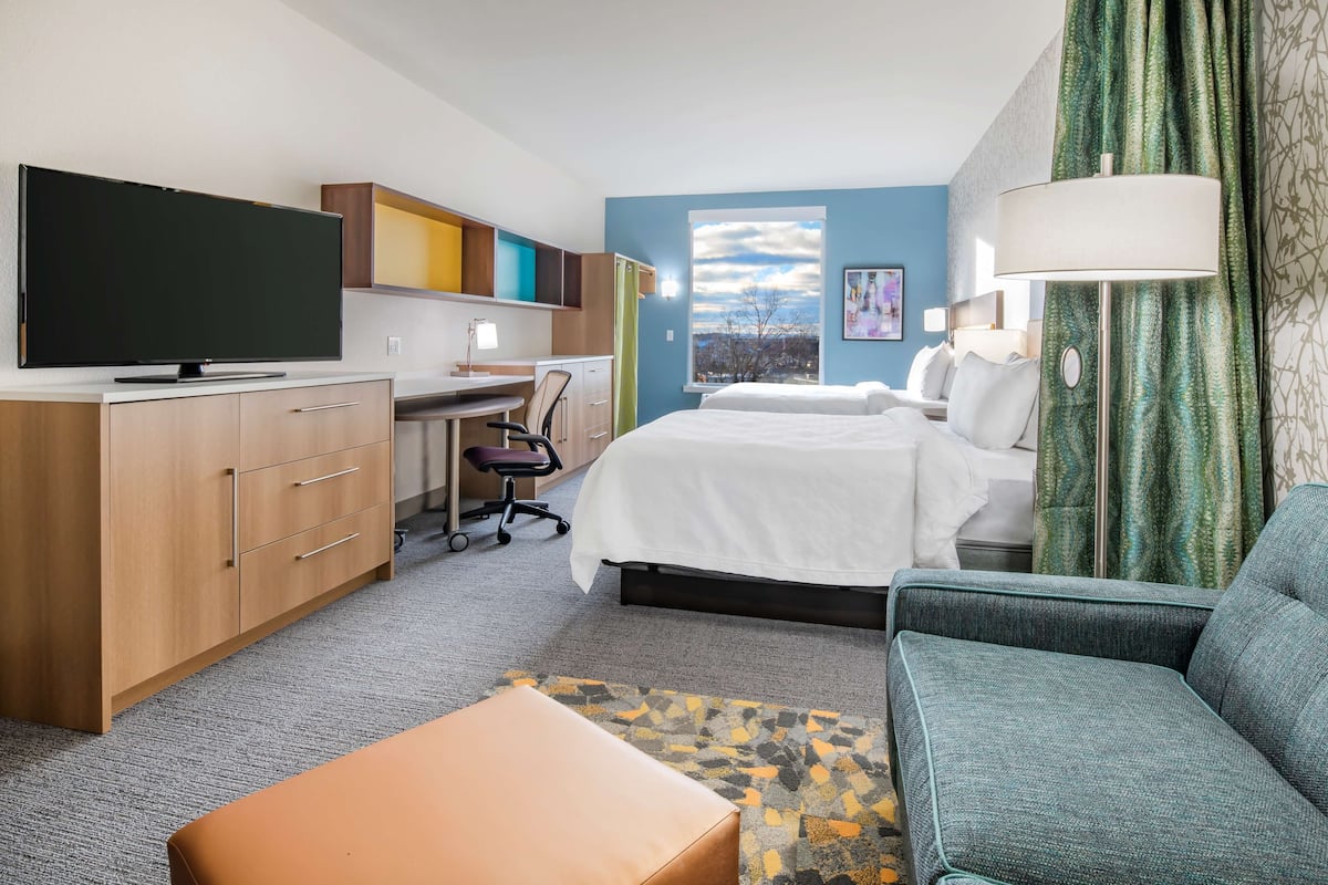 Ein Hotelzimmer mit Bett, Schreibtisch, Fernseher, Sofa und einem Fenster mit Blick.