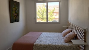 Un dormitorio con cama, ventana, un cuadro y un radiador.