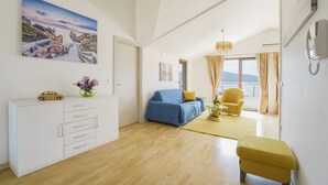A modern living room with a wooden floor, a sofa, a small table, and a view of the sea through a large window. - Tivat Montenegro (Tivat)