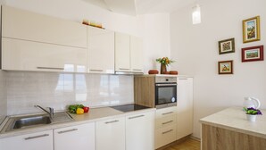 A modern kitchen with white cabinets, a stainless steel sink, and a built-in oven. - Tivat Montenegro (Tivat)