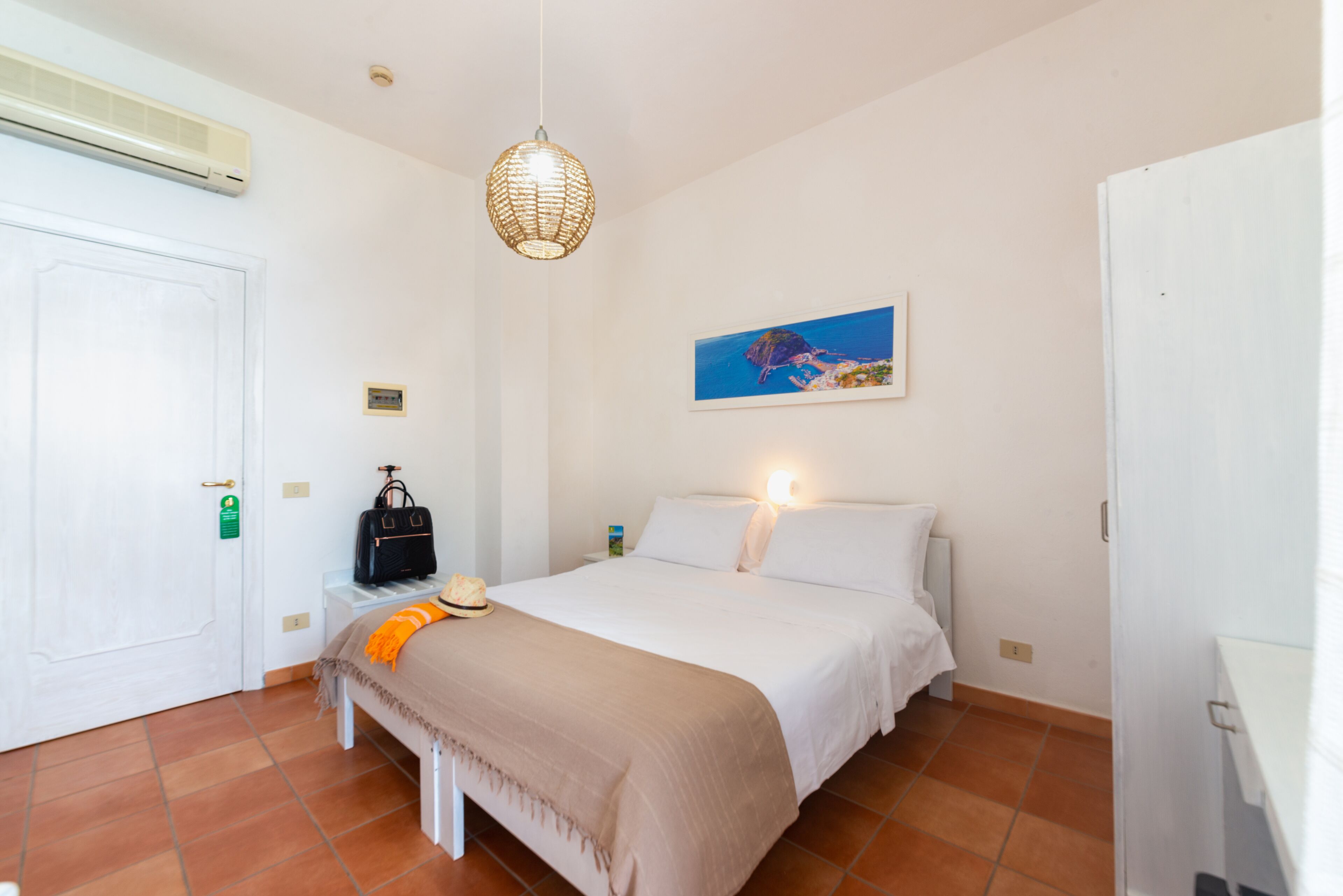 Un dormitorio con cama, mesita de noche, lámpara y un cuadro en la pared.