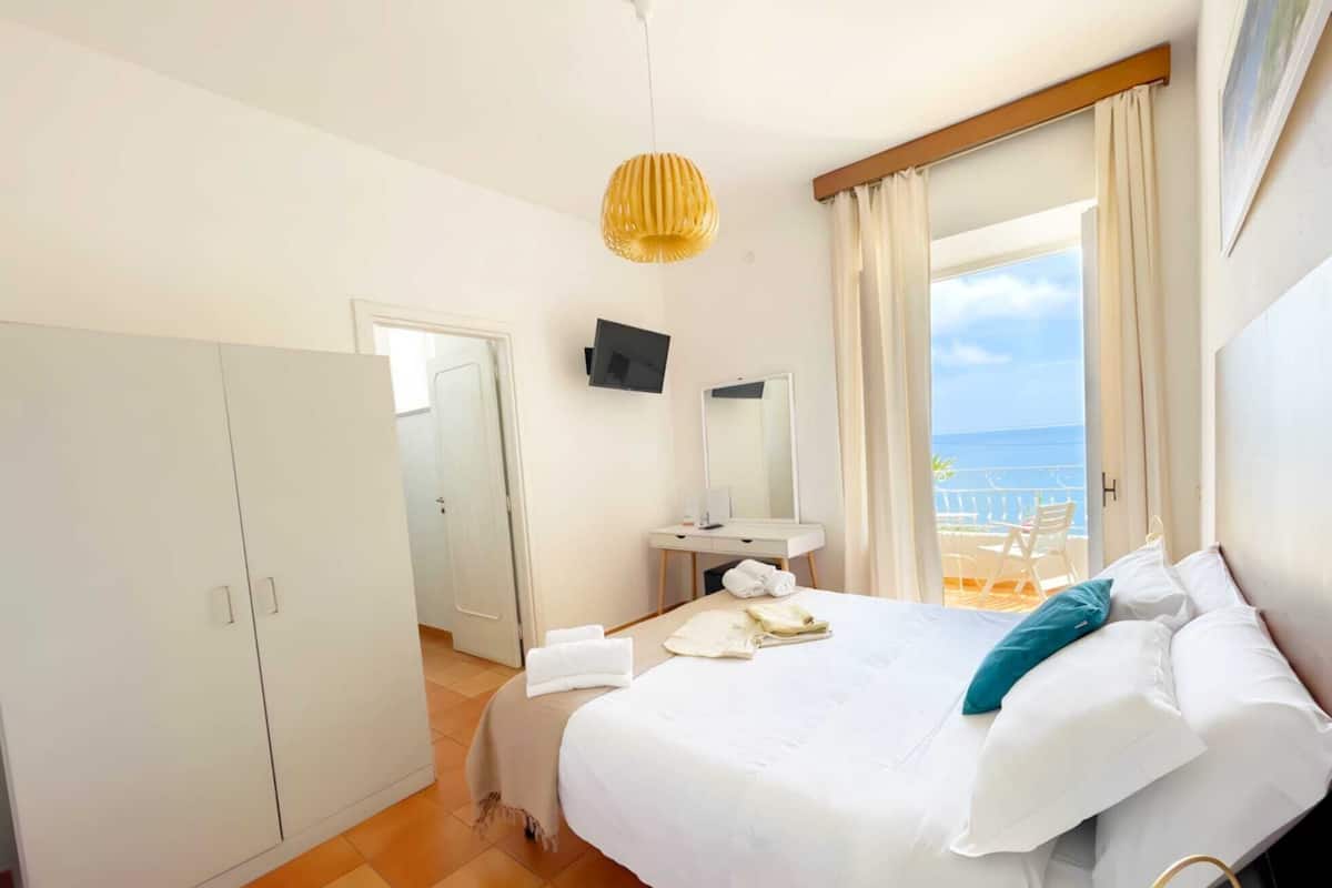 Ein Hotelzimmer mit Bett, Schreibtisch, Fernseher und Meerblick.