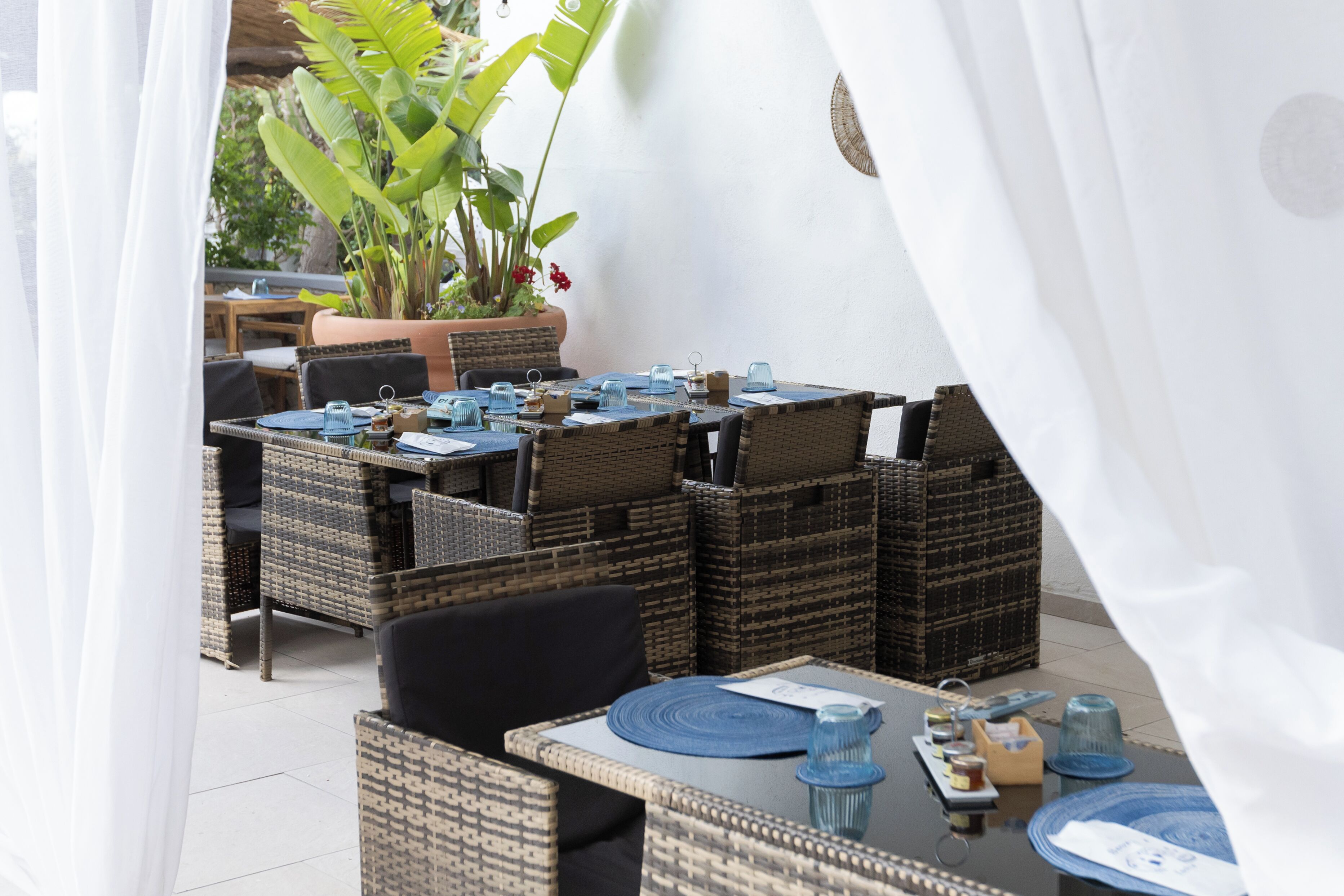 An outdoor dining area with wicker furniture and blue glassware.
