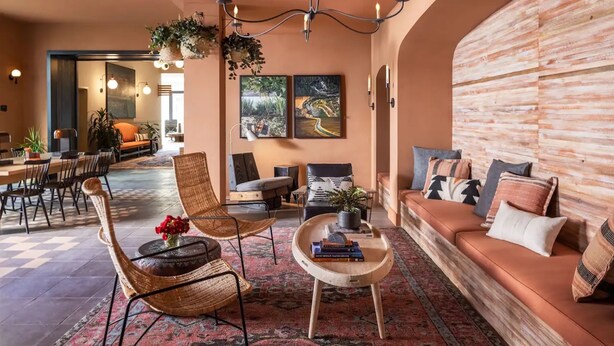 A spacious living area with a sofa, chairs, a coffee table, and artwork on the walls. - El Capitan Hotel (Merced)