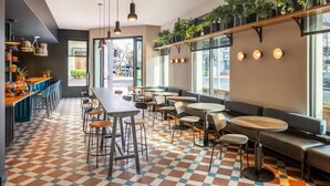 A cafe with a checkered floor, multiple seating areas including tables and benches, hanging plants, and a bar counter with stools. - El Capitan Hotel (Merced)