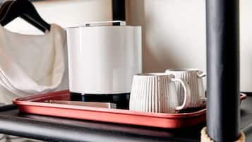 A red tray with a white mug and a white container on a black surface.
