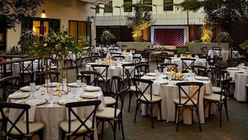 An outdoor dining area with round tables and chairs, set up for a formal event.